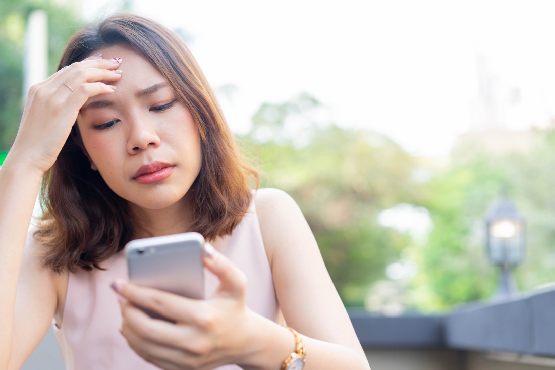 Person looking at phone with distressed expression